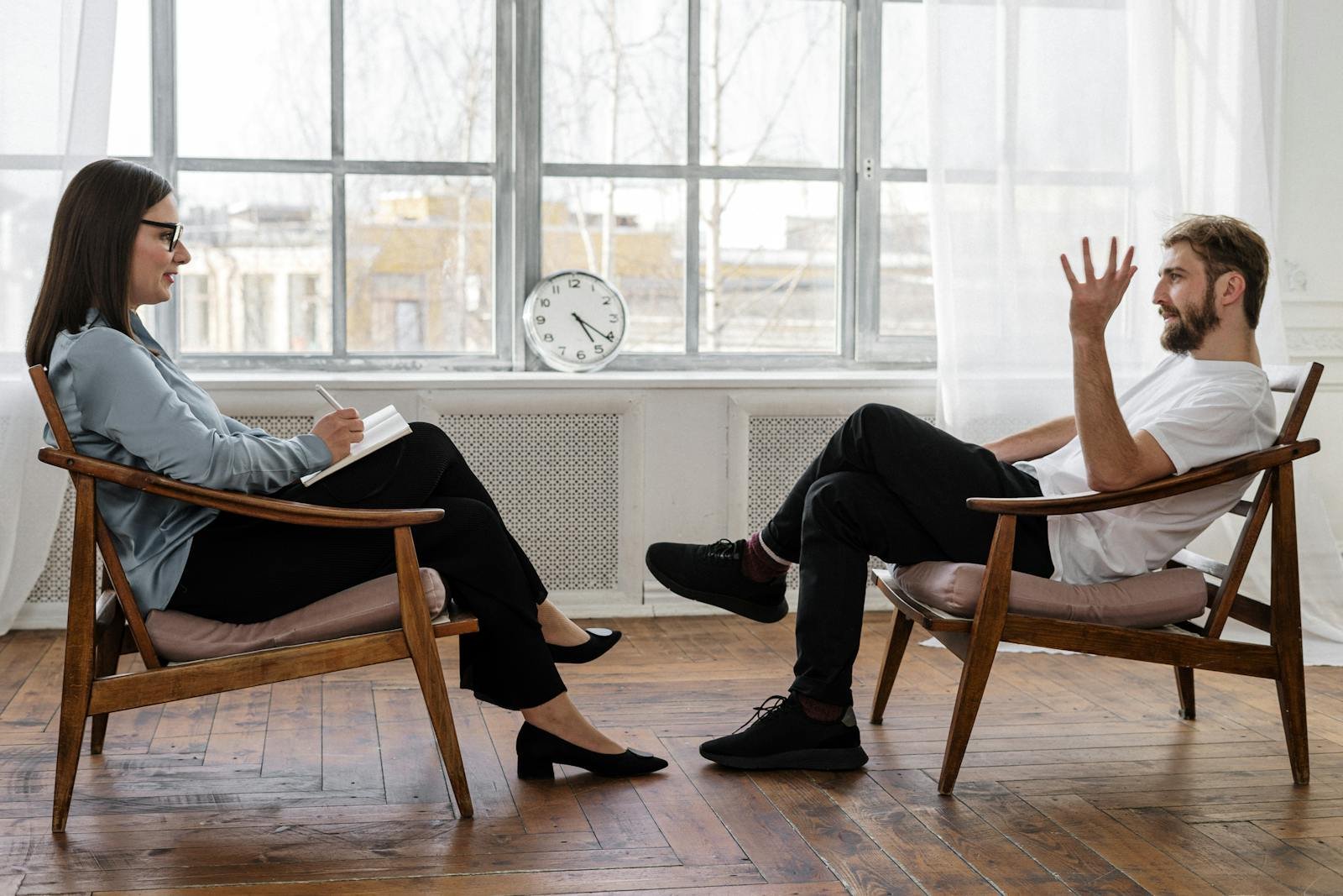 Person in Black Pants and Black Shoes Sitting on Brown Wooden Chair, humanism